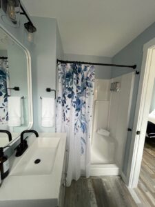 Modern guest bathroom at The Homestead Palisade with sink, black fixtures, white towels, and blue leaf shower curtain