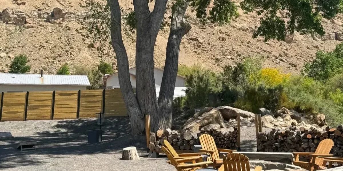 Homestead Palisade midweek adventure: outdoor seating area with wooden chairs and a fire pit. Mountain backdrop.