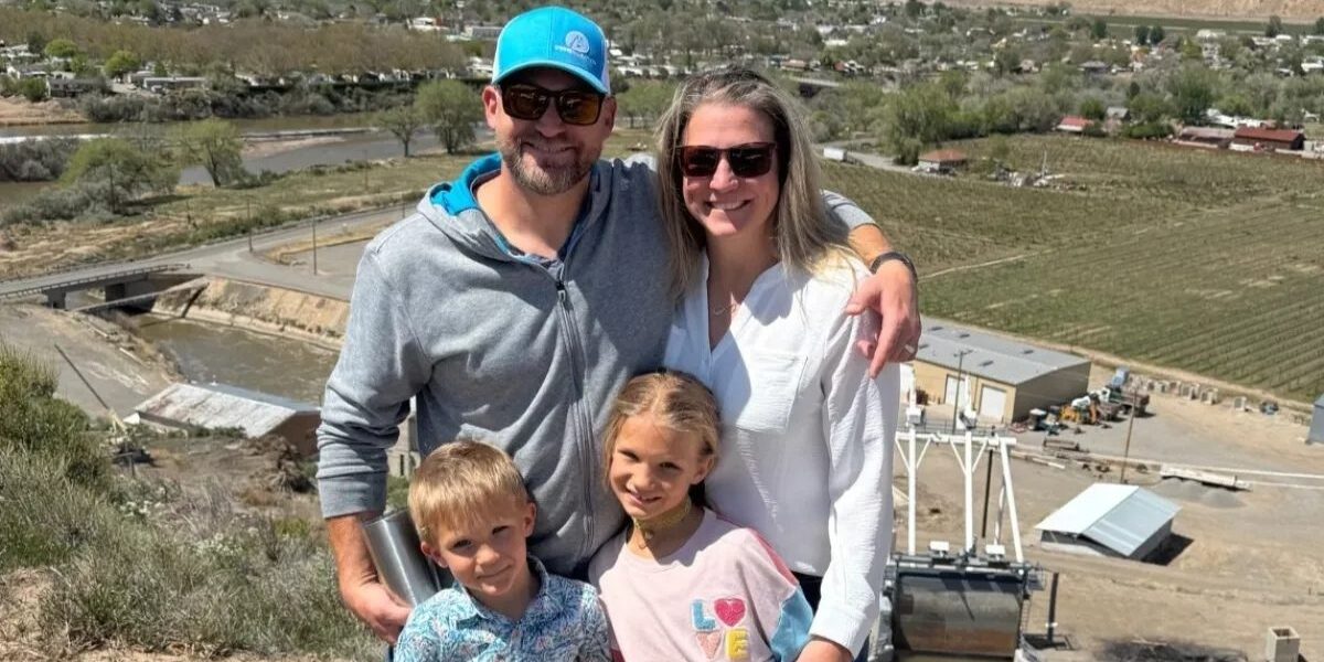 The Homestead Palisade family-owned business. Family of four smiling outdoors.